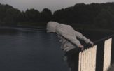 Mężczyzna z pętlą na szyi i liną przymocowaną do barierki